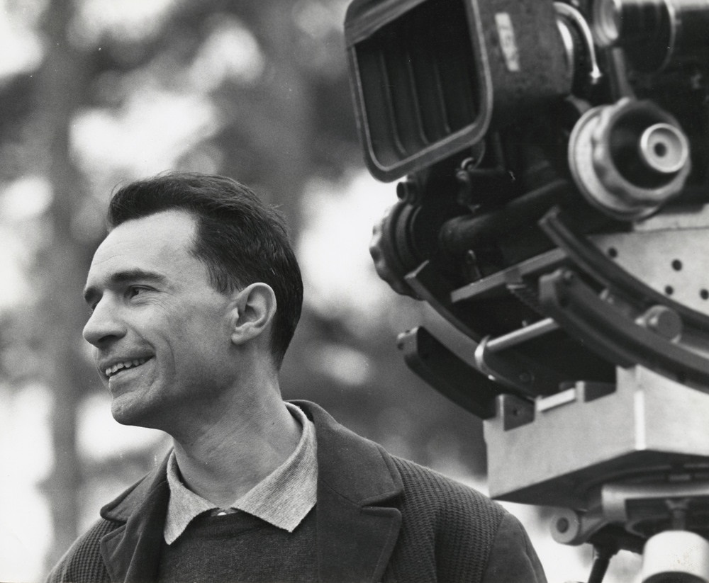 head and shoulders of Jacques Rivette next to a film camera.