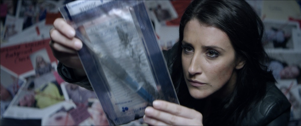 A woman examines a document in a plastic sachel.