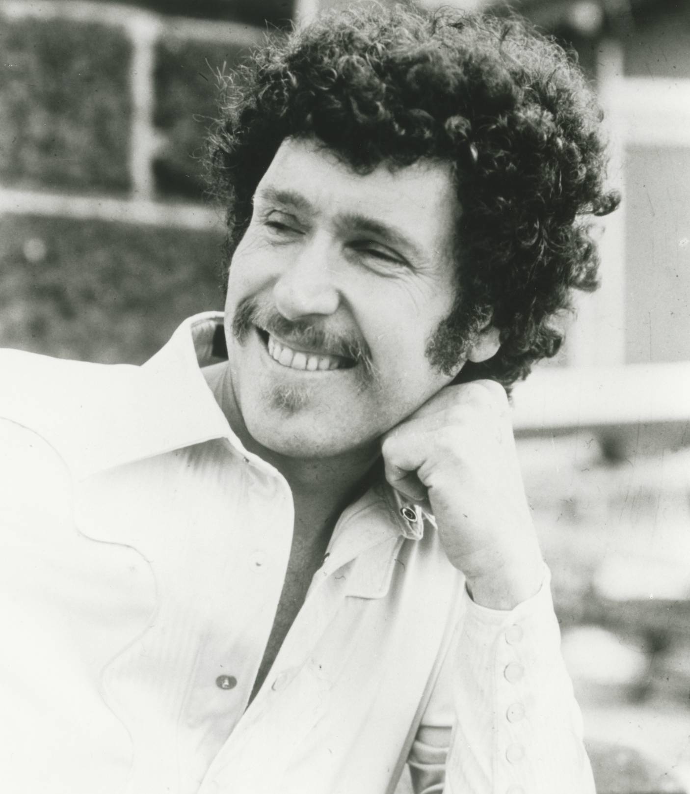 Publicity still of singer-musician Max Merritt in an open-necked shirt, head leaning on his hand and looking away from the camera