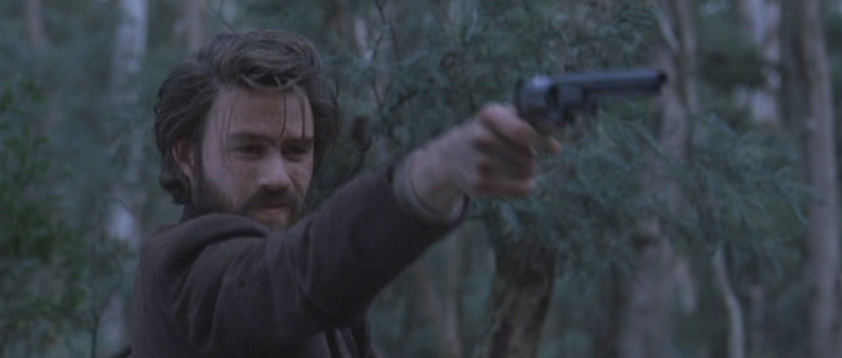 A young bushranger points a gun at someone