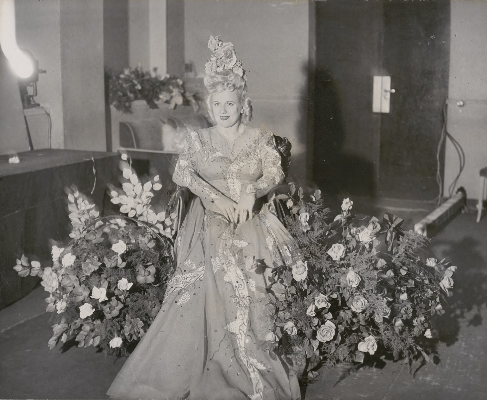 Marjorie Lawrence wearing an exotic dress and surrounded by flowers.