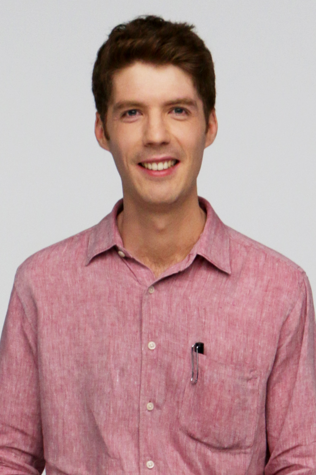 A portrait of a man in a collared shirt. He has a pen in his pocket.