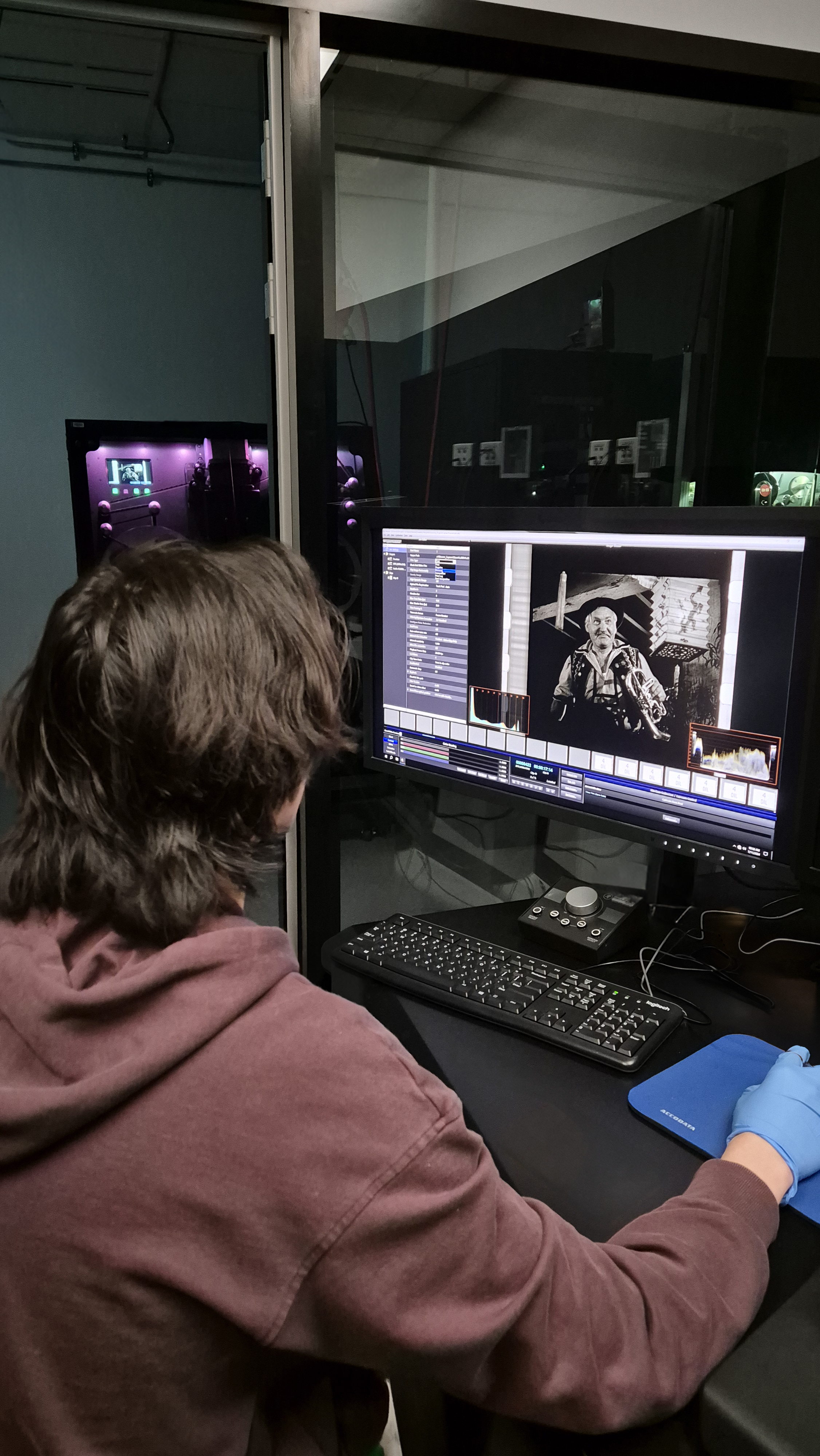 A staff member at the National Film and Sound Archive examines an image from a black-and-white film on a computer monitor.