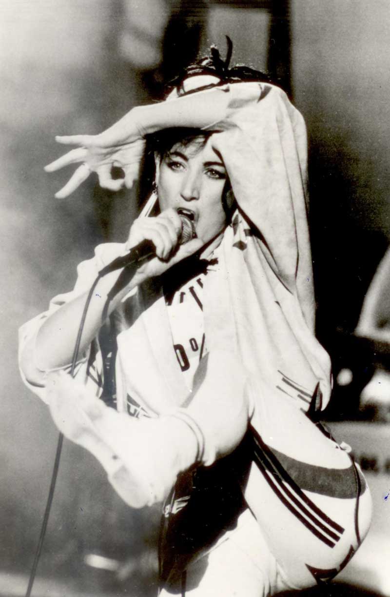Image of singer Grace Knight performing on stage. She is singing into a microphone and kicking her leg up in the air.