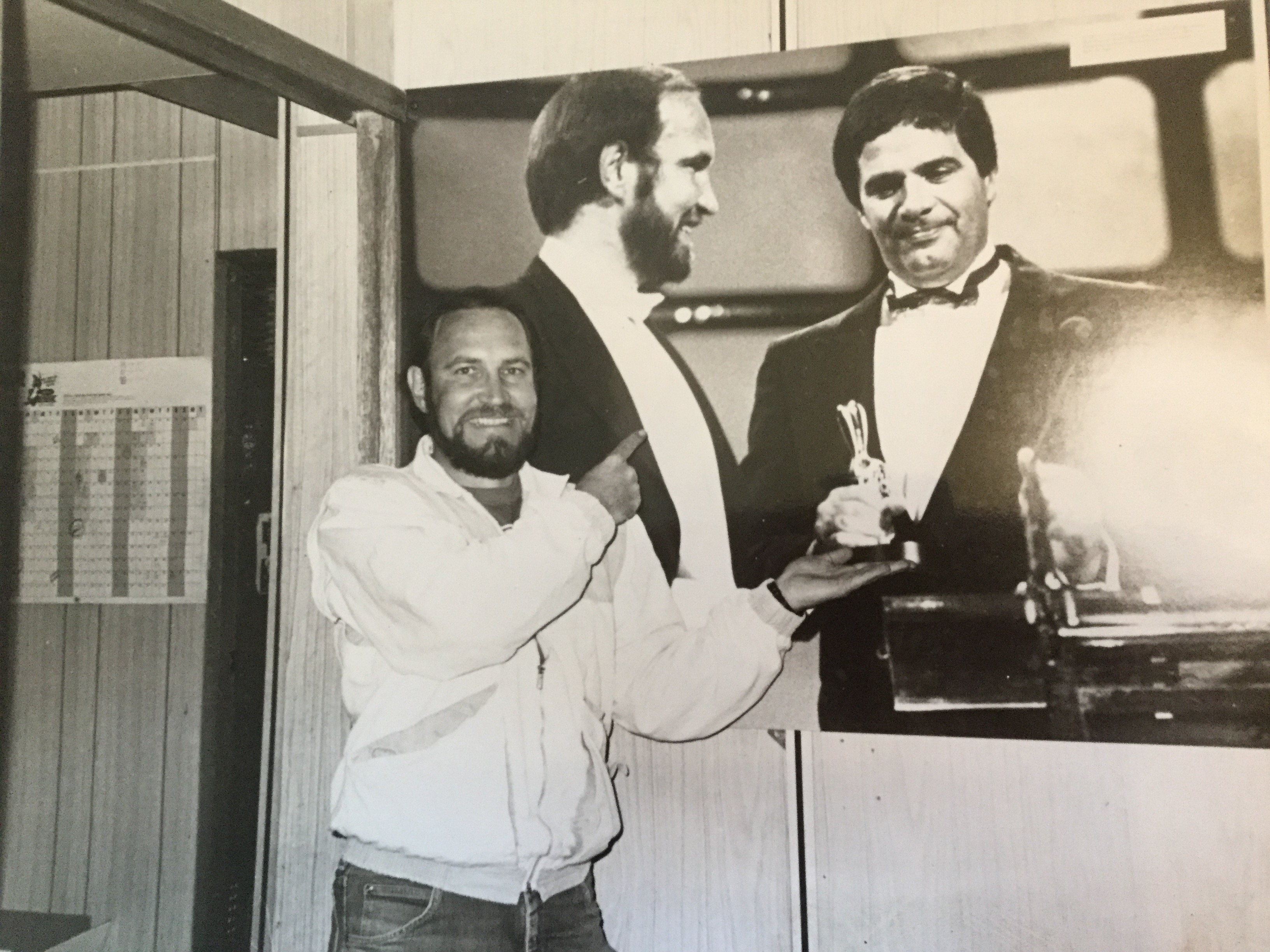 Producer Harvey Shore standing in front of a blown up image of himself with Simon Townsend holding a Logie Award.