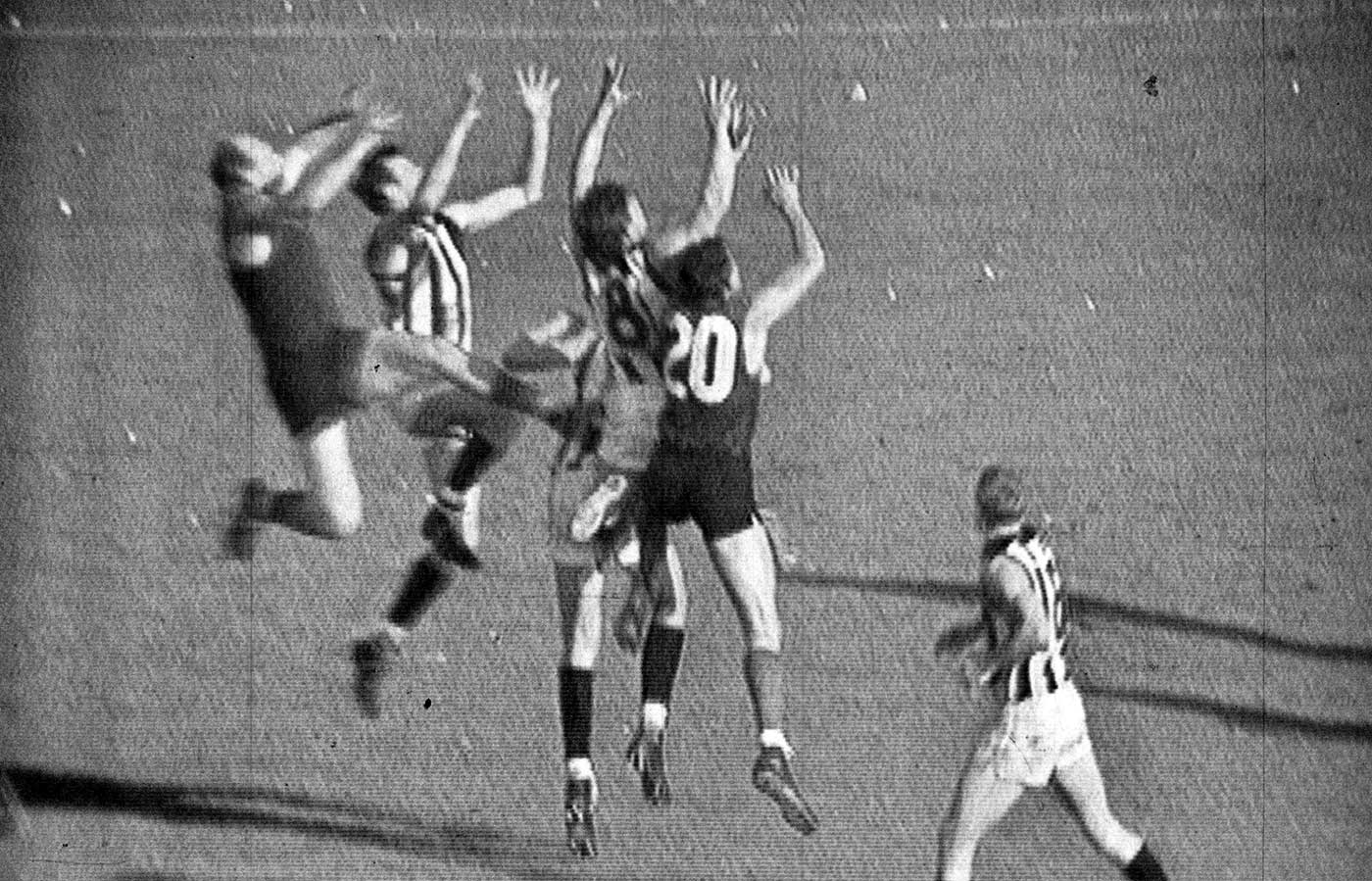 Australian Rules Football players jumping for the ball in the 1964 grand final match.