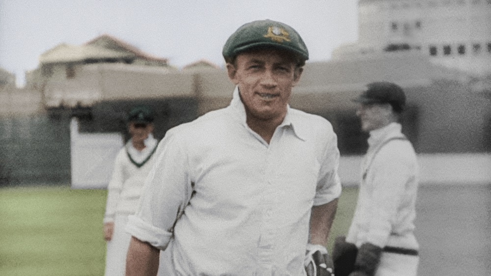 Colourised film still of Donald Bradman walking off the cricket pitch.