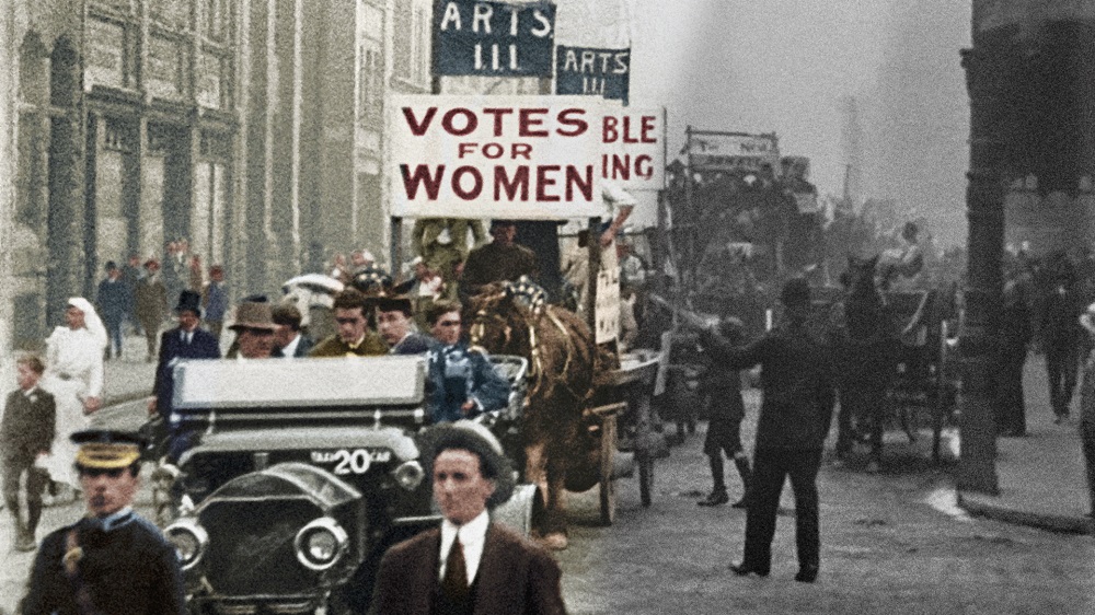 Colourised film still of a procession of university students marching for women