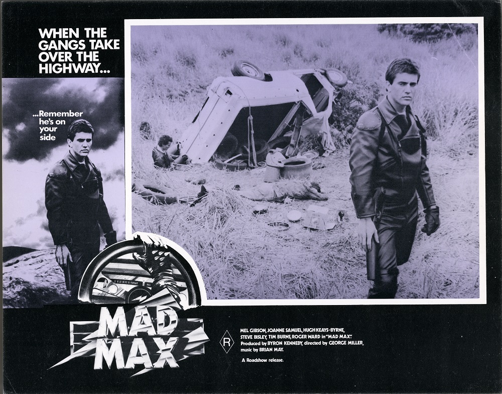 Lobby card for Max Max shows Max (Mel Gibson) next to an overturned car
