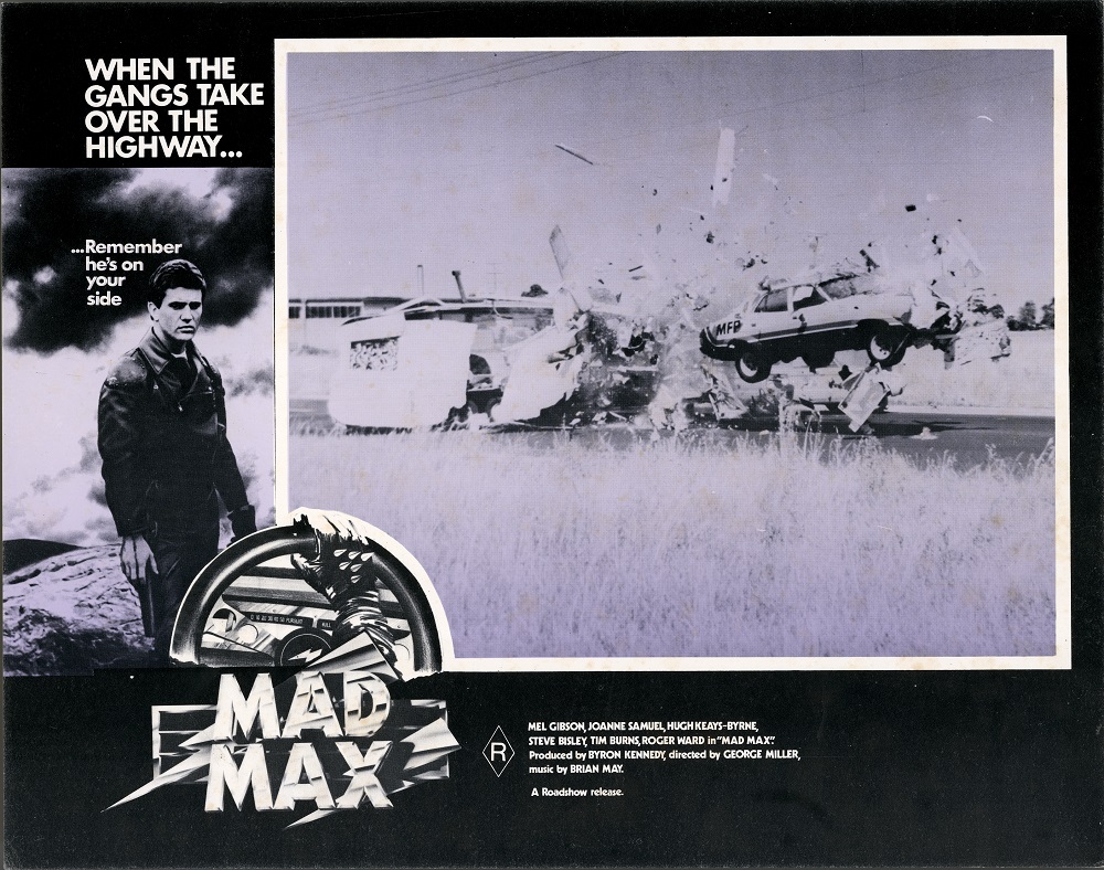 Max Max 1 lobby card shows a car flying through the air and smashing though a caravan.