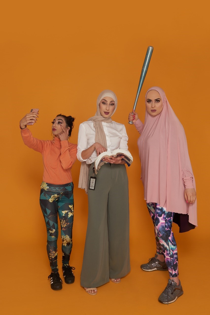 Three Muslim women, one looking at her mobile phone, another with a text book and the third brandishing a baseball bat