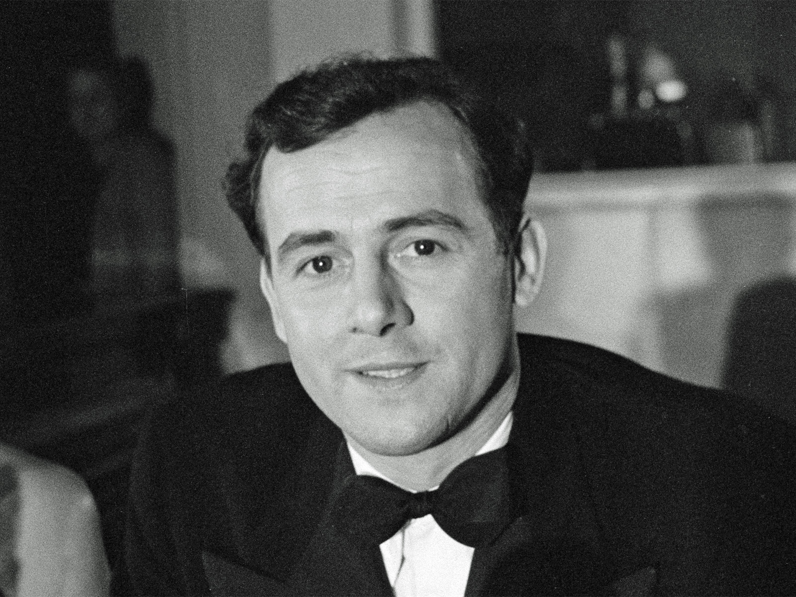 Head and shoulders shot of a man in a suit and bow tie looking at camera.