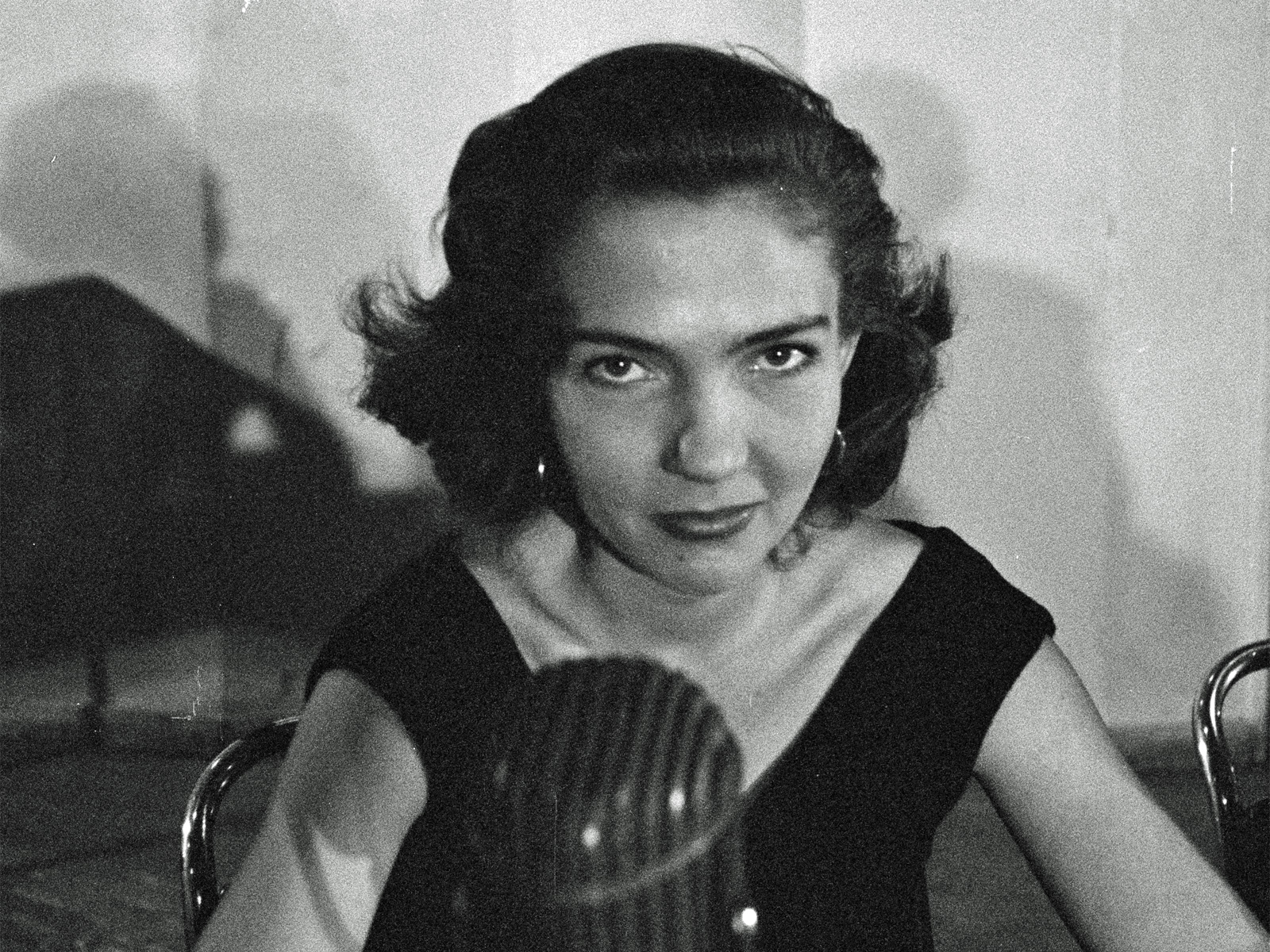 Head and shoulders shot of a young woman looking at camera with a radio mic in front of her.