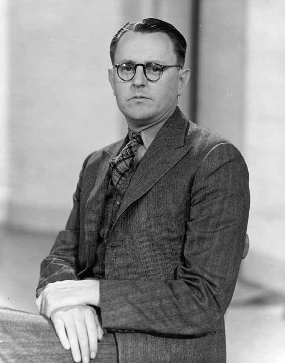 Portrait of Ken G Hall with his hands crossed over each other. 