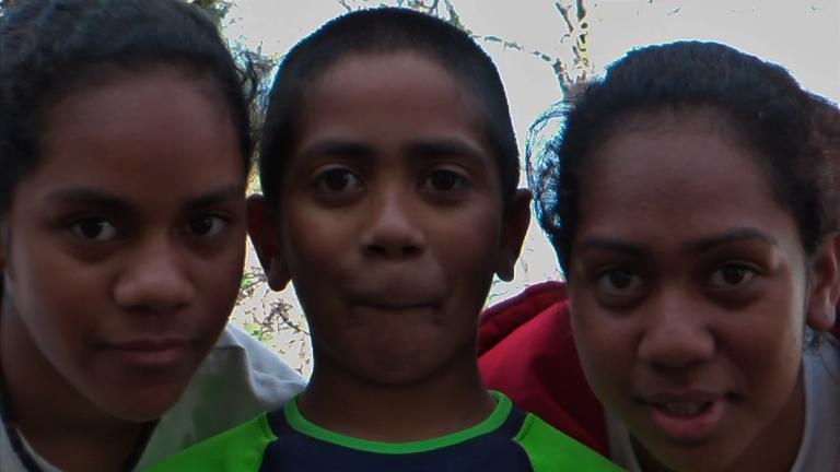 Close up of three young kids looking into the camera.