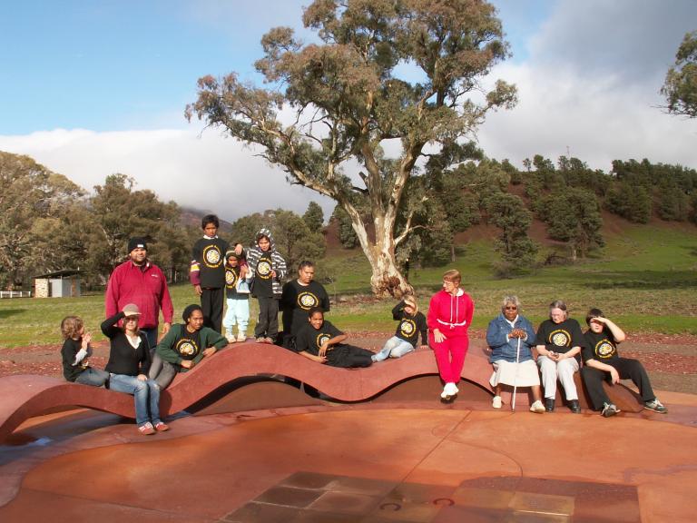 Group of people sitting on a wavy bench in a park. Group of people sitting on a wavy bench in a park.