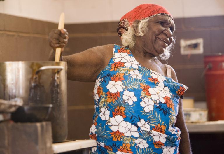 A woman in the kitchen stirring a large pot