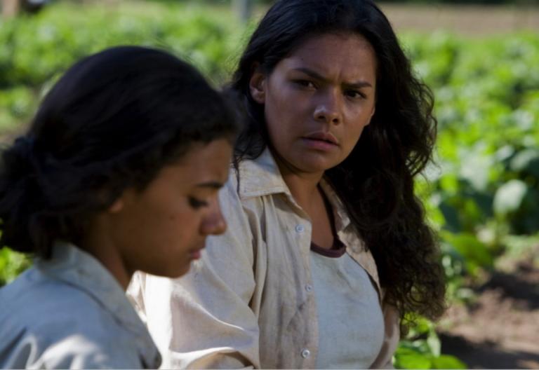 A woman in a farm looking over to a girl in the foreground