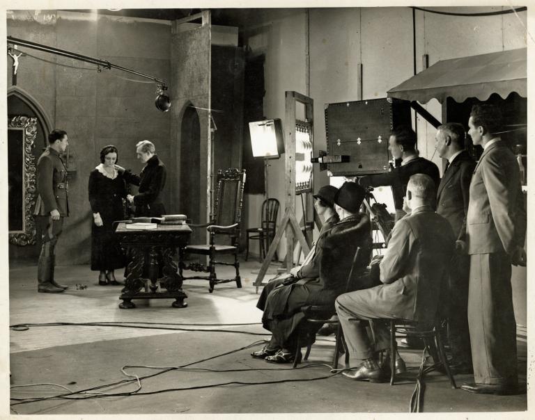 A film studio where you can see the director, crew and actors filming a scene.
