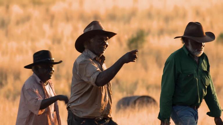 Three Aboriginal men walking in the outback