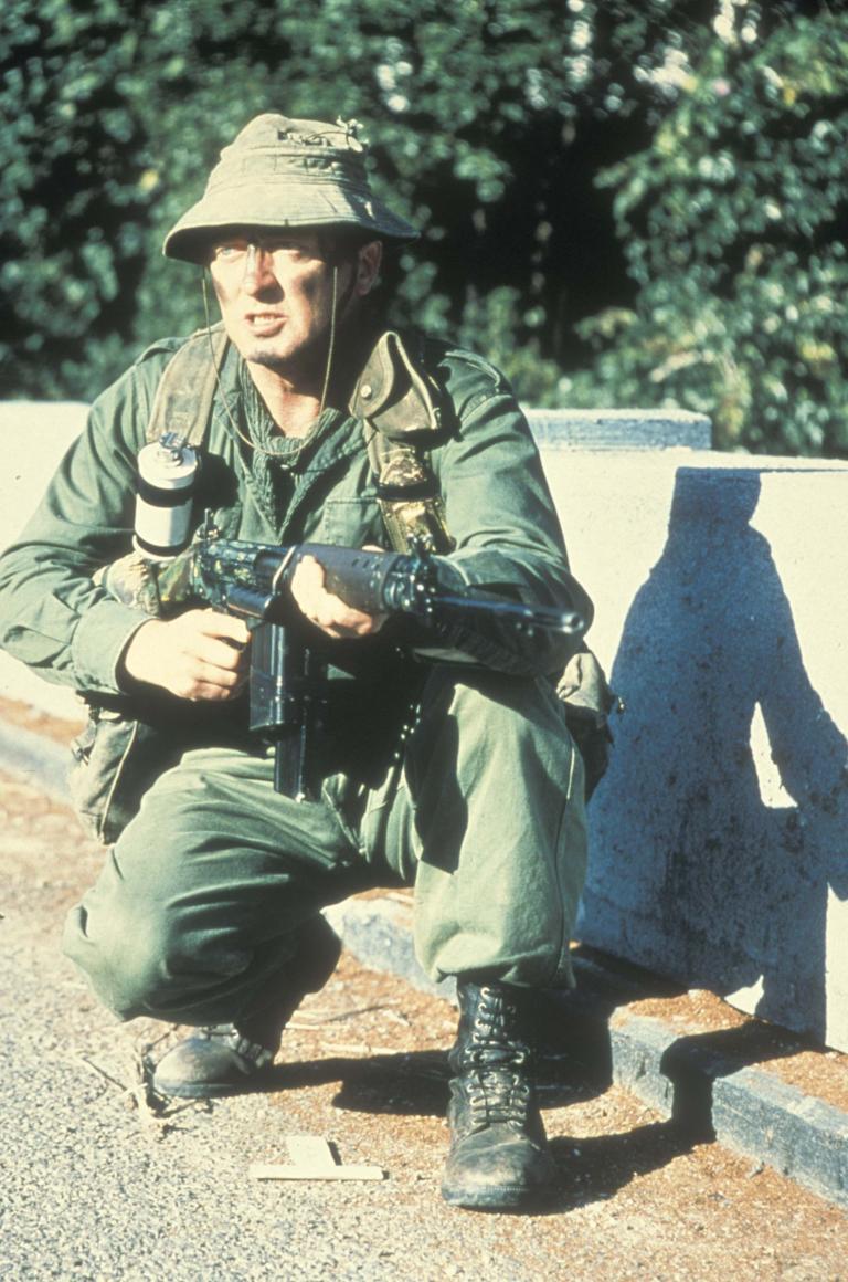 Graham Kennedy in The Odd Angry Shot crouching with gun