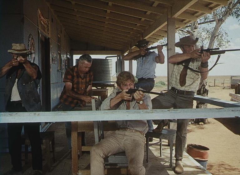 Five men on the balcony of an outback house, four of whom are pointing rifles in the same direction Five men on the balcony of an outback house, four of whom are pointing rifles in the same direction