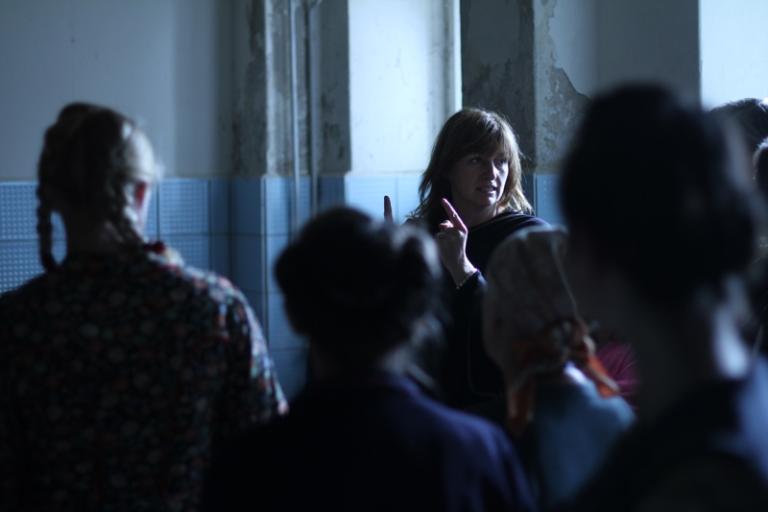 Cate Shortland directing Lore Director Cate Shortland directs a room full of people. We see the other people from behind and out of focus.