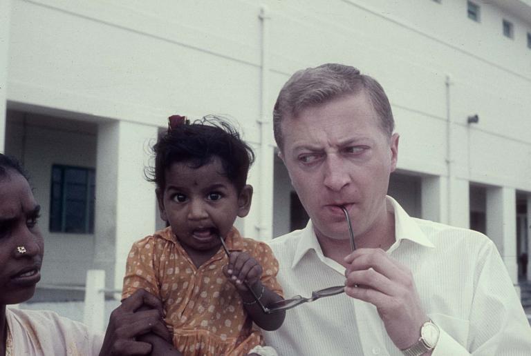Graham Kennedy in India with a young mother and her baby girl. The baby girl is chewing on Graham's glasses.