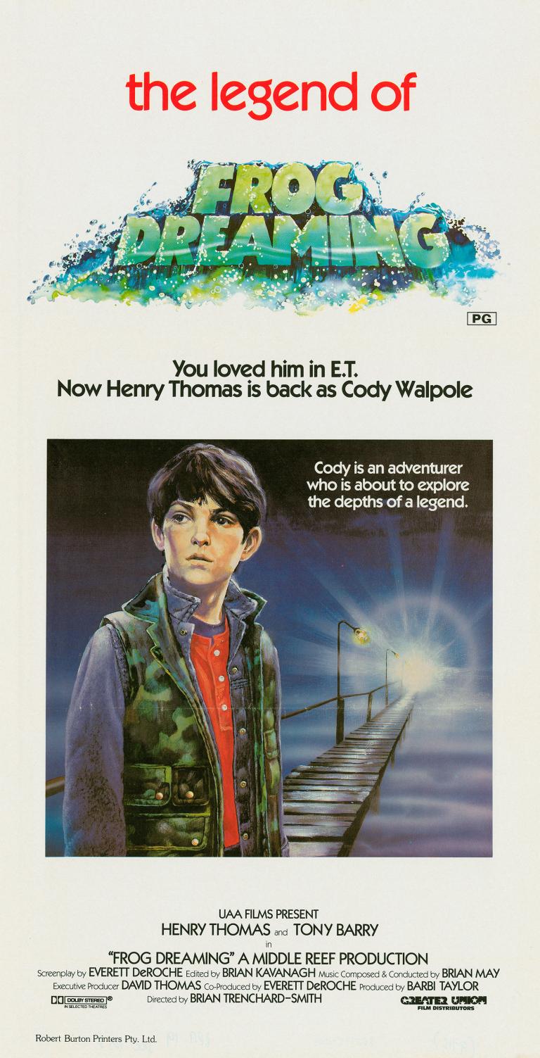 Frog Dreaming Daybill Poster Poster art for a film called 'the legend of frog dreaming' showing a young boy wearing a camouflage vest standing on a platform or pier with a light shining in the distance. The film title and credits are above and below the image.