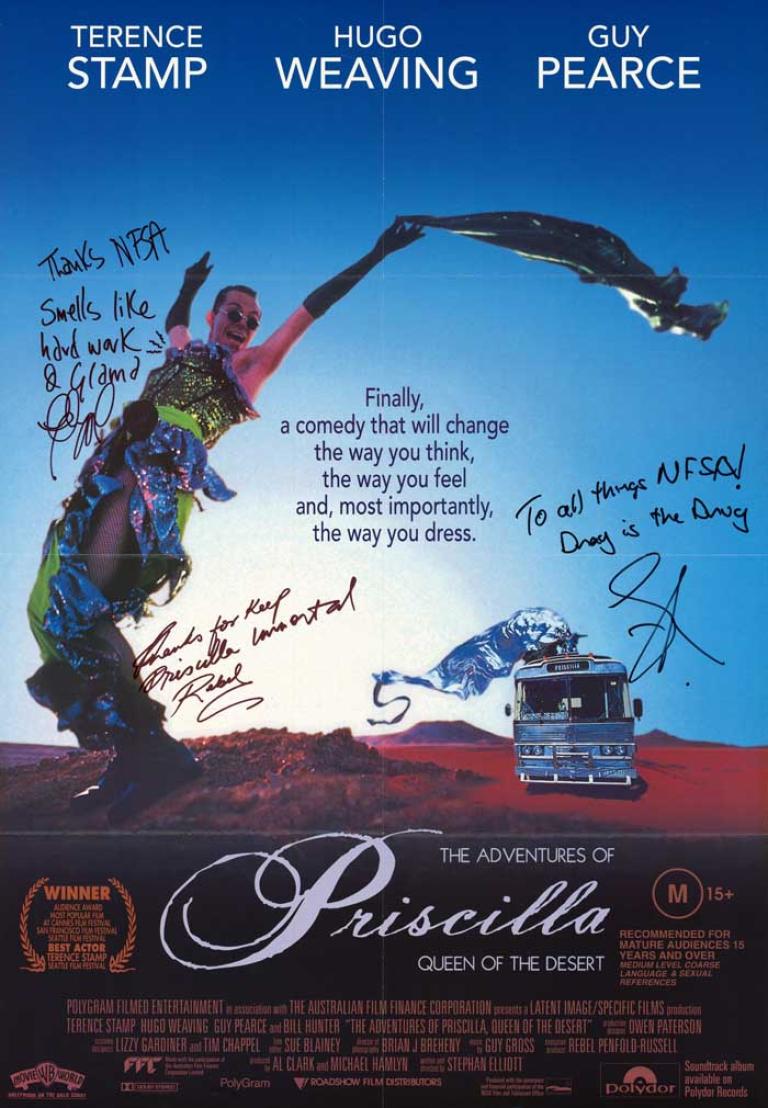 Hugo Weaving with arms in the air, wearing green and blue sequined outfit, holding green scarf. Silver bus with a silver draped figure on the roof is in the background to the right. Header text list of main cast members in white block print.