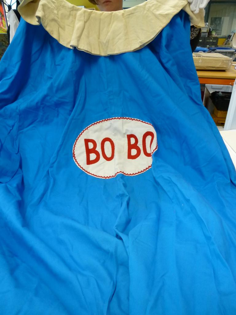 Bobo the clown cape, c1961-65 Blue clown cape with white fringe and white oval in centre with Bobo stitched in red letters