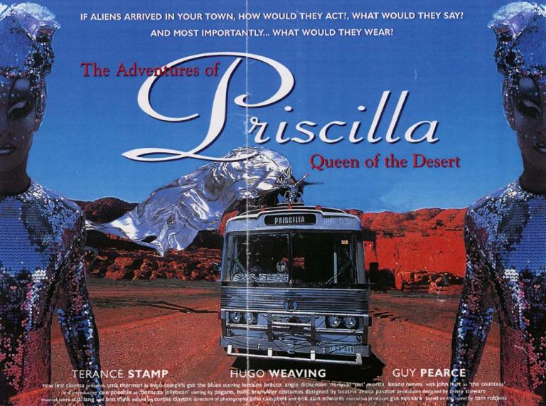 Image of bus travelling in desert setting with a drag queen riding on top dressed in a silver, flowing costume. Image is bordered by two drag queens dressed in silver sequined costumes and headresses.