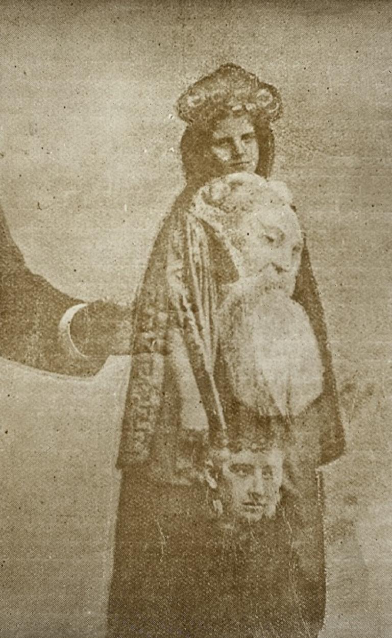 Sepia tone glass slide showing a female spirit Sepia tone glass slide showing a female spirit with a man and boy superimposed over her. An arm is reaching in from left side of image.