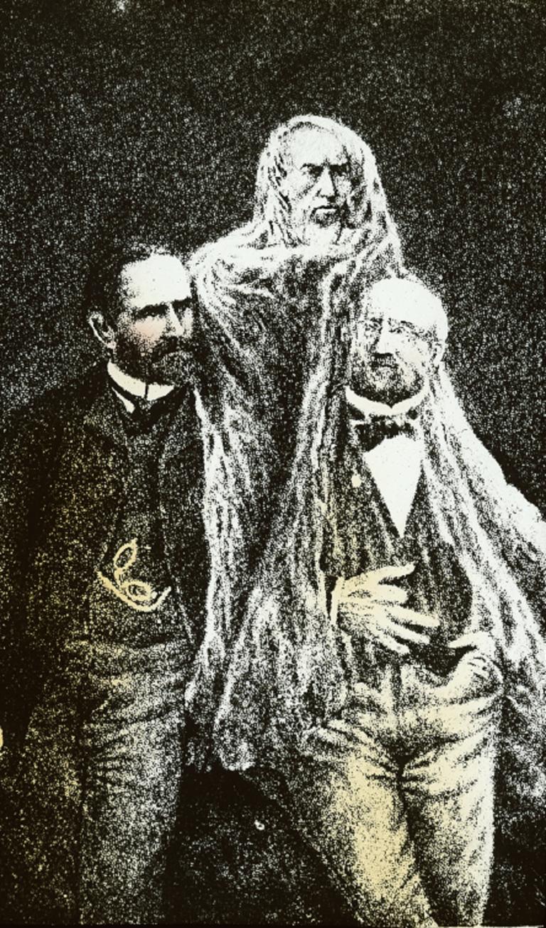 Spirit glass slide by Édouard Isidore Buguet Colour glass slide showing two men standing together, a spirit in white robes hovering between and through them
