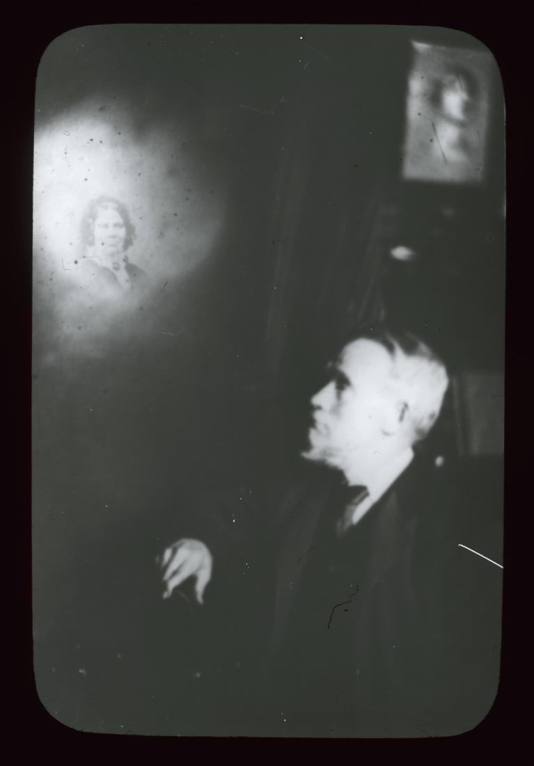 Man looking up at an illuminated spirit Black and white glass slide showing the upper body left profile of a man looking up to his right at an illuminated spirit.