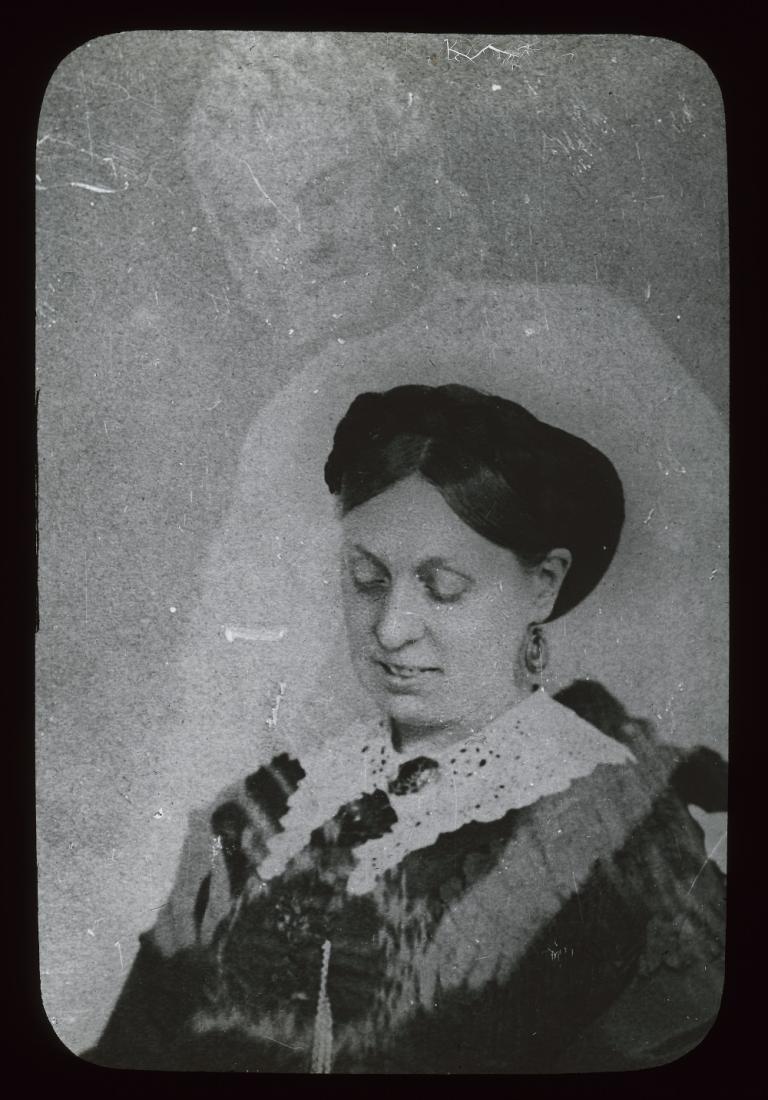 Emma Hardinge Britten with a spirit Black and white glass slide showing the upper body of a woman looking down, a spirit leaning over her, resting arms over her shoulders