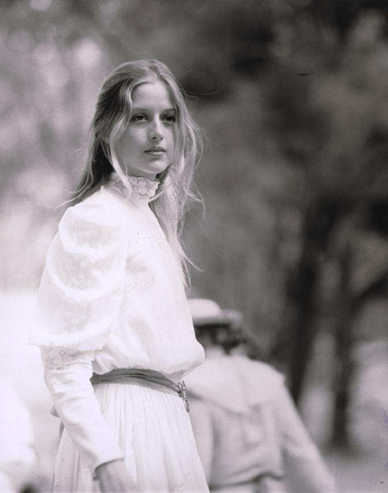 Anne-Louise Lambert as Miranda outside wearing white and looking into the distance