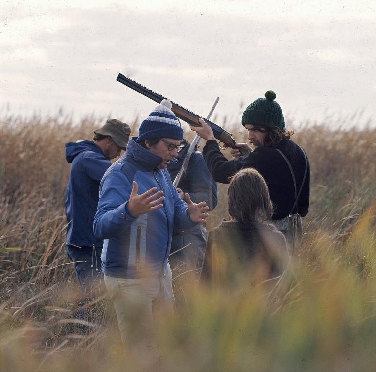 Director Henri Safran talking with actor Greg Rowe, with other actors and crew present, on the outdoor set of Storm Boy