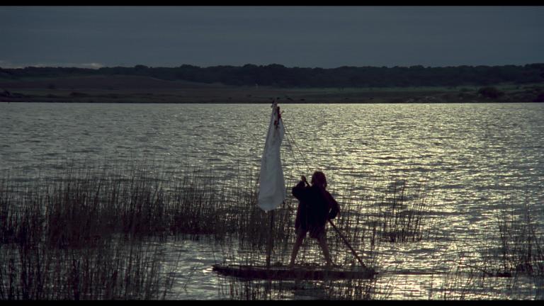 Greg Rowe as Storm Boy sailing his punt in the dark mangroves in a scene from Storm Boy