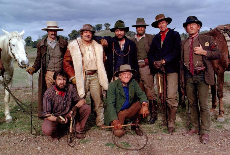 Seven cast members pose with Kirk Douglas on set wearing their costumes for the film.