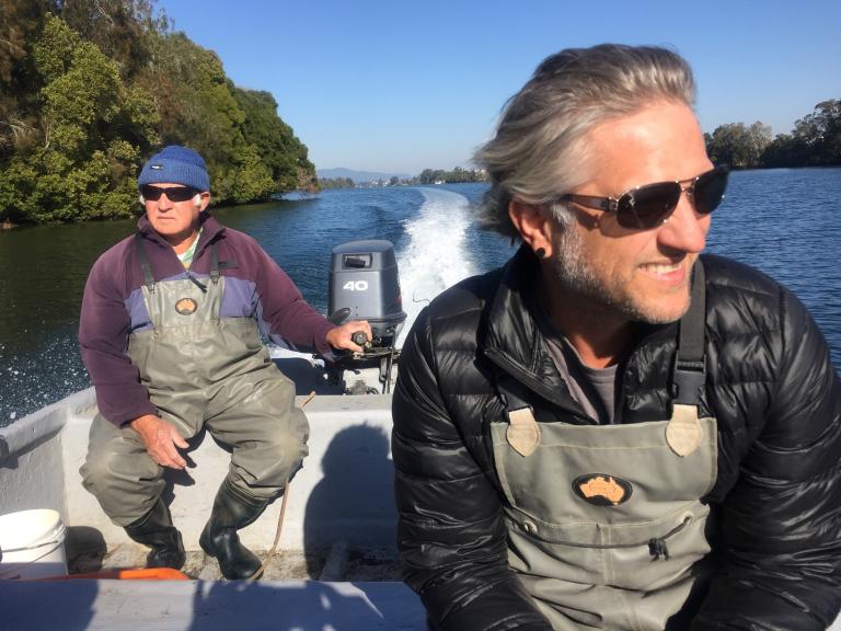 Two men in a fishing boat on a river.