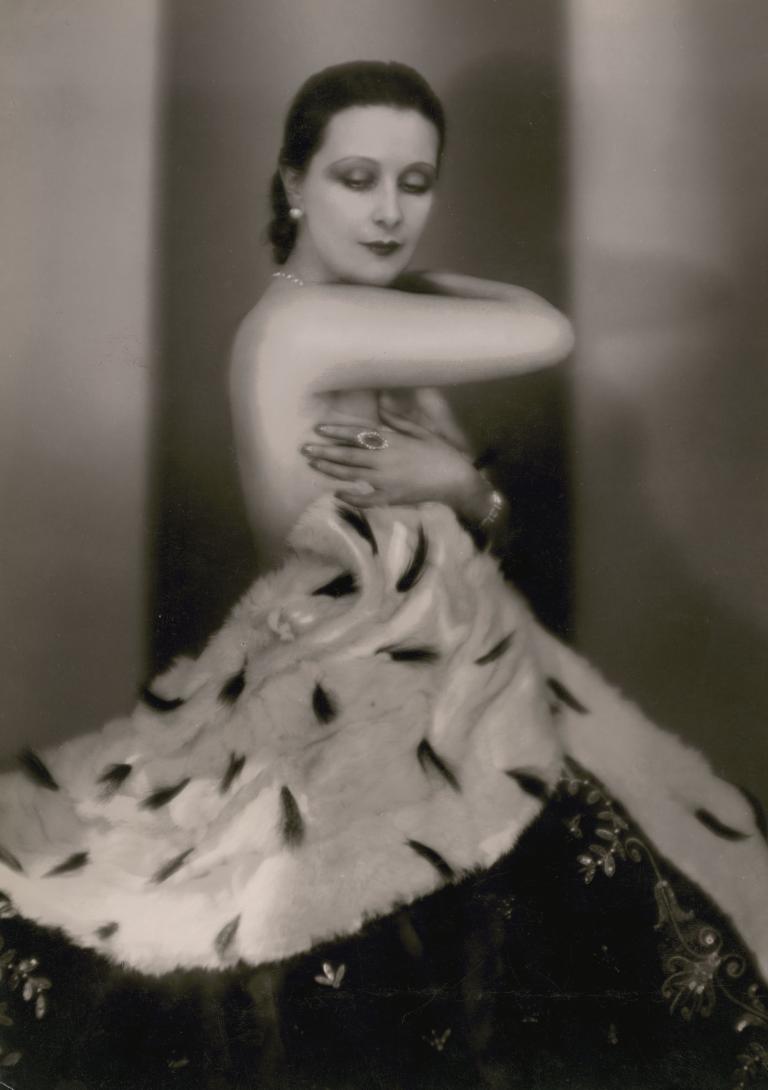 Actress Lil Dagover stands with eyes closed and arms wrapped around herself.