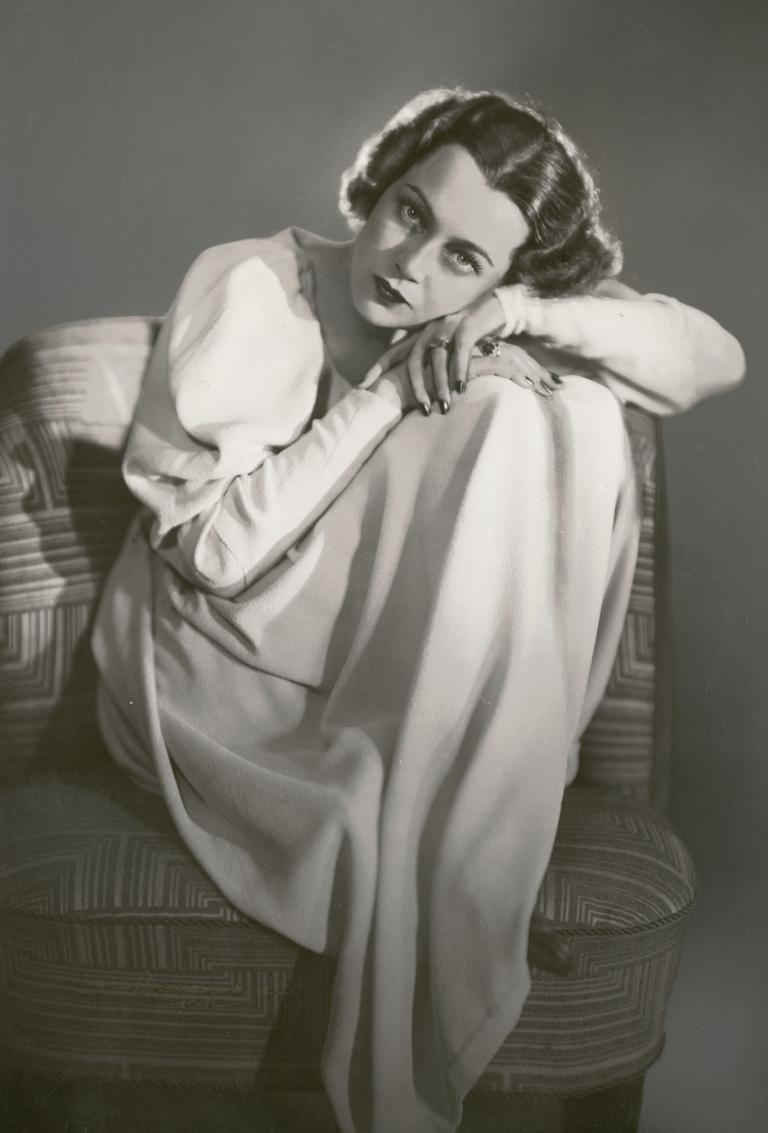 Portrait of Baroness Luli von Hohenberg who is seated and resting her head on her hands.