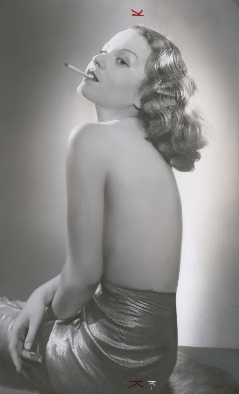 Portrait of actress Jenny Gerhardt, head titled upwards and smoking a cigarette.