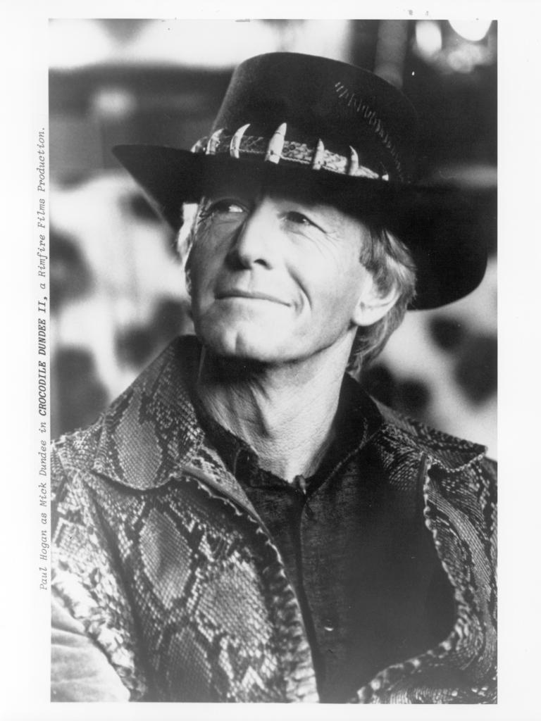 Paul Hogan as Mick Dundee Black and white production still of Mick Dundee (Paul Hogan). He is wearing Mick's trademark hat with crocodile teeth around the band and a crocodile skin jacket.