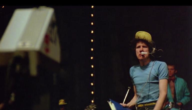 Geoffrey Rush, looking angry and wearing a headset microphone on the stage of the Sydney Opera House