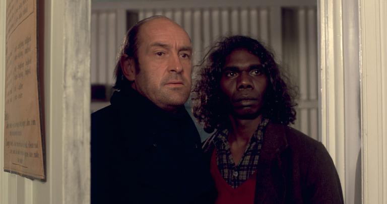 Peter Cummins as Hideaway Tom and David Gulpilil as Fingerbone Bill looking through an open door nervously