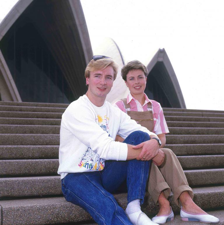 Ice skaters Jayne Torvill and Christopher Dean posing on the steps of the Sydney Opera House.