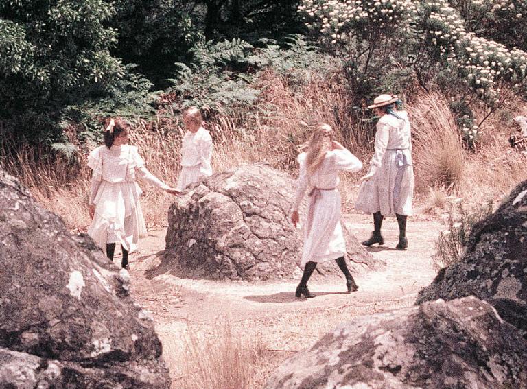Four girls circle rock The four schoolgirls walk in a circle around a rock