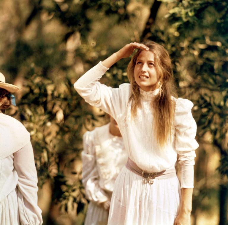 Miranda (Anne Lambert) looks up at Hanging Rock while shading her eyes from the sun